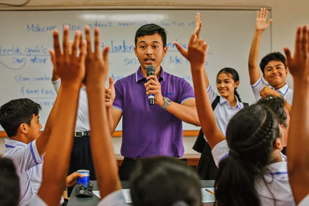 A mentor in a purple shirt leads a career talk as students raise their hands