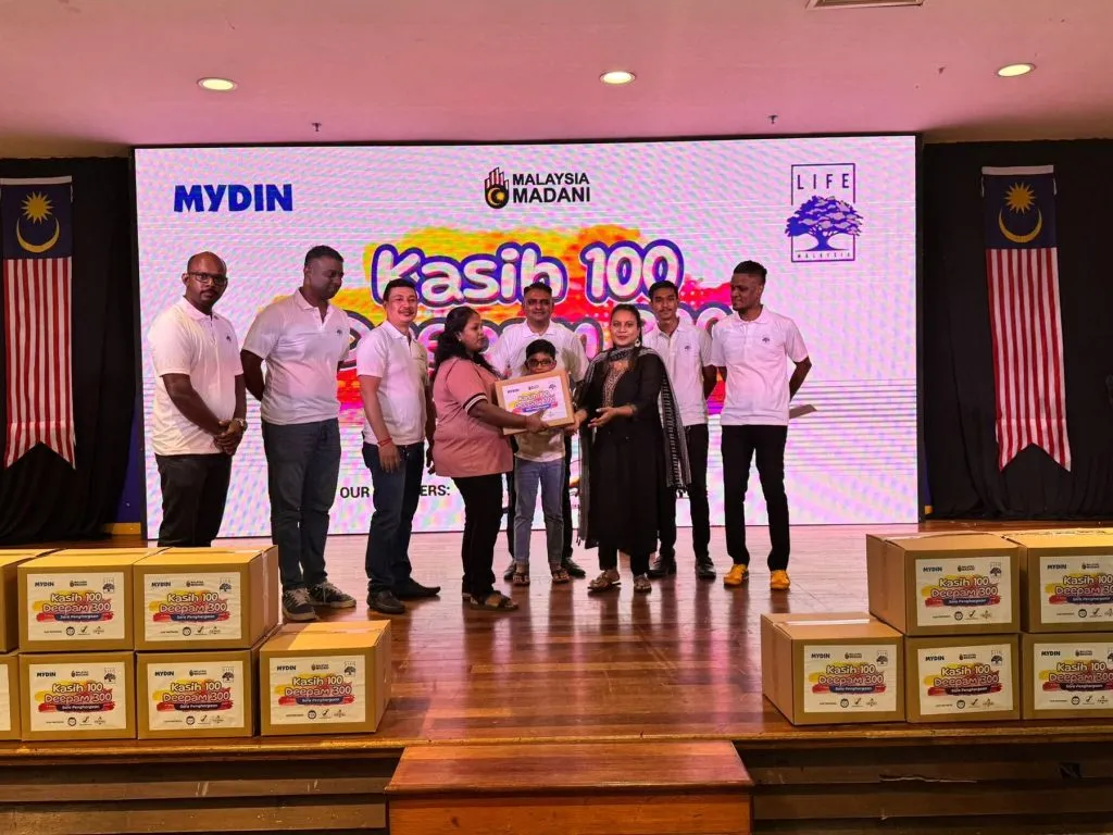 LIFE Malaysia volunteers hand over Kasih 100 Deepam 300 food aid boxes on stage, 2025