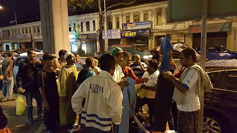 Volunteers handing out food to homeless people at night in Kuala Lumpur, 2015