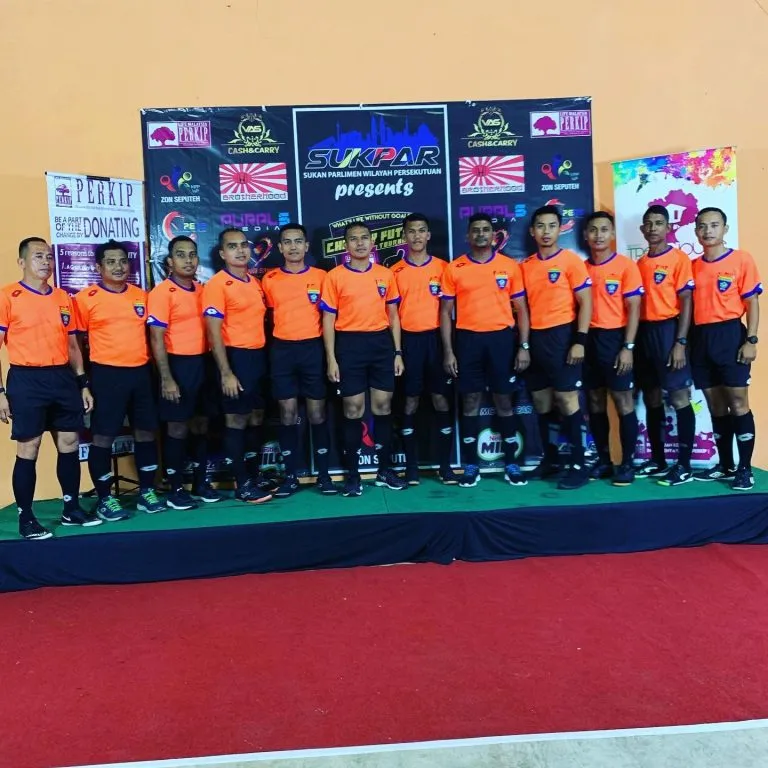 Team in orange jerseys on the stage at the charity futsal