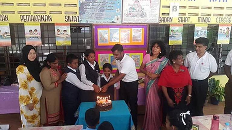 Pupils and volunteers cut a cake at Ladang Escot Tamil School, 2016