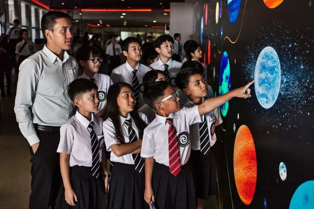 Students in school uniform looking at a planetarium exhibit at a science centre
